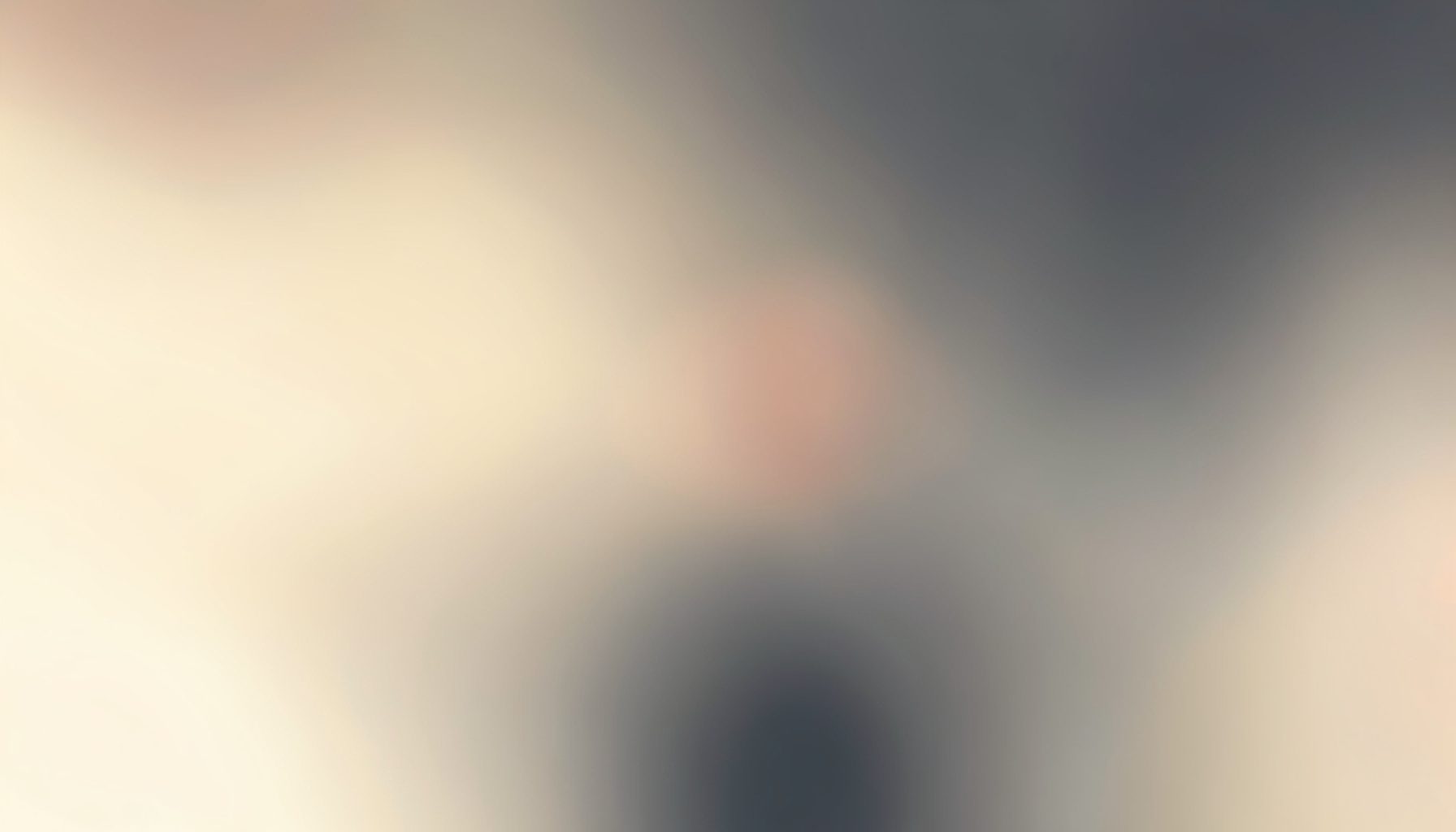 A warm abstract gradient blending soft cream and muted charcoal tones, evoking a calm and focused creative workspace.